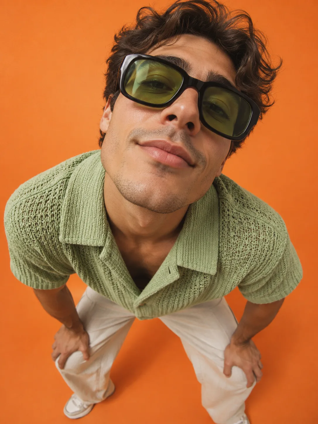 Playful fisheye menswear portrait against an orange background