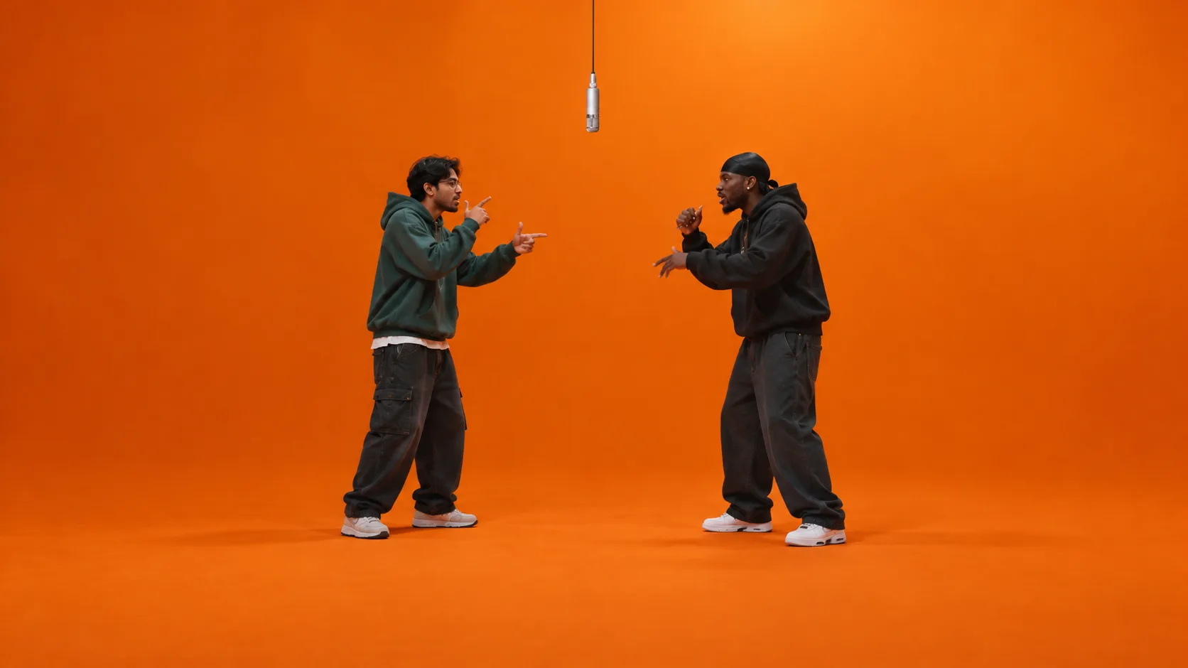Two men in hoodies trading lines face to face in the orange booth